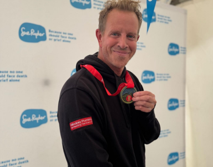 Paul from Hinckley Plumbing & Heating holding his medal after the Great North Run for Sue Ryder